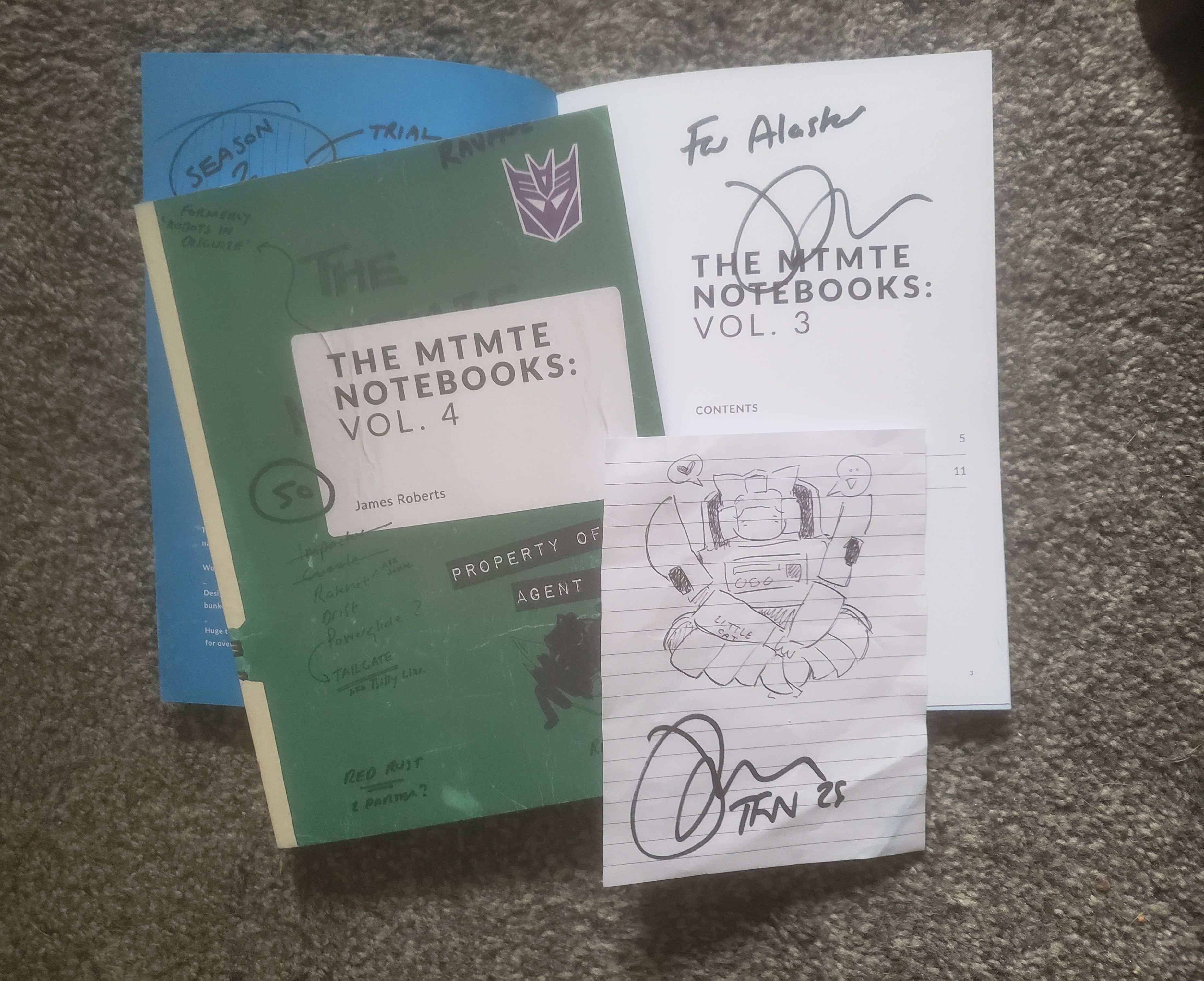 Volumes 4 and 5 of the MTMTE notebooks (Volume 5 being open on the first page, where it's signed by James Roberts.) On top of the books is a slightly crickled doodle of Tailgate on lined paper, also signed by James Roberts.